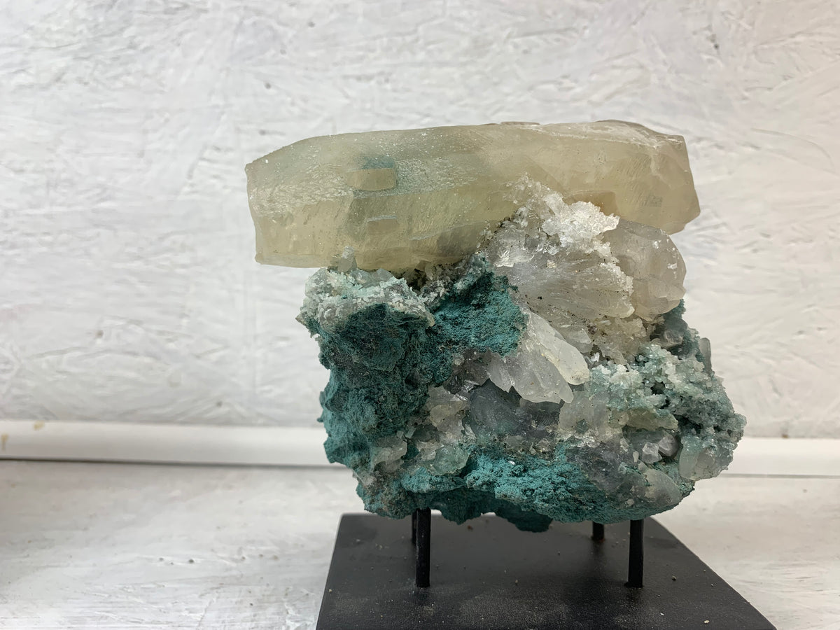 Natural green calcite on calcite mineral specimen from Brazil displayed on a black stand