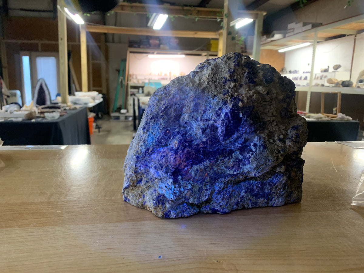 Close-up of blue lapis lazuli mineralization within natural host rock under UV light