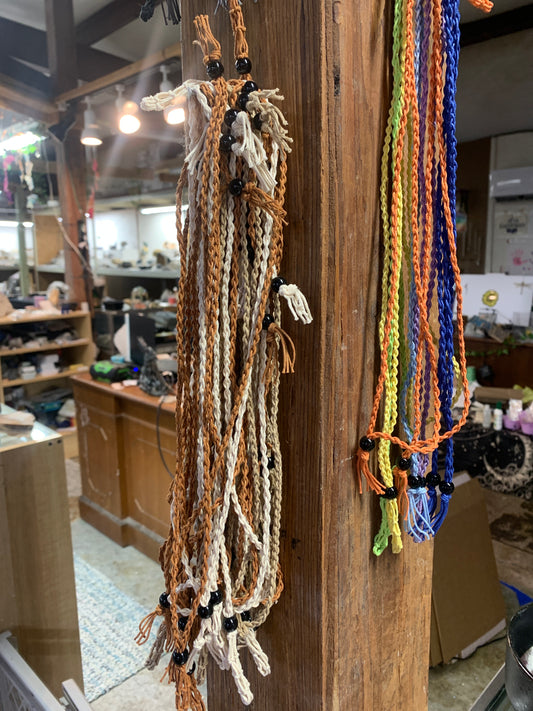 Adjustable macramé stone holder necklaces in assorted colors hanging at Earthforged Rock Shop