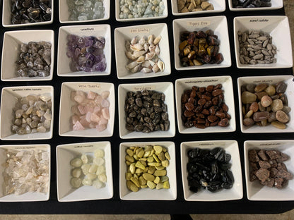 Small natural gemstones and mineral specimens displayed in individual trays at Earthforged.